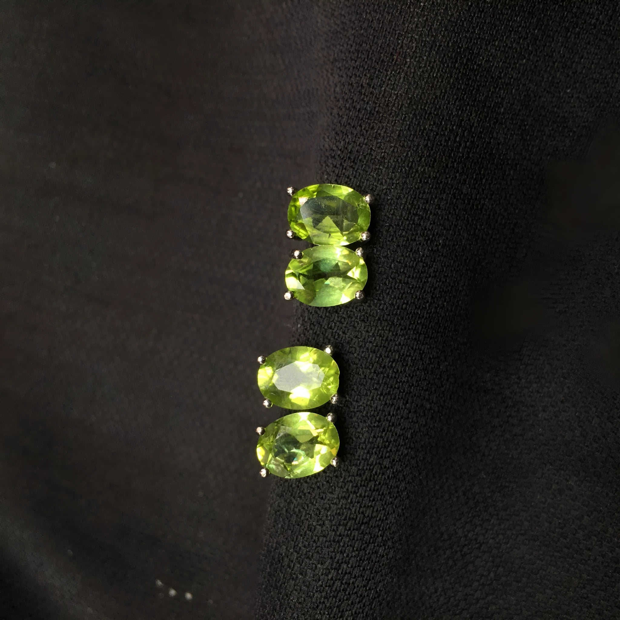 Close-up of natural grass green olivine stud earrings in S925 sterling silver settings.