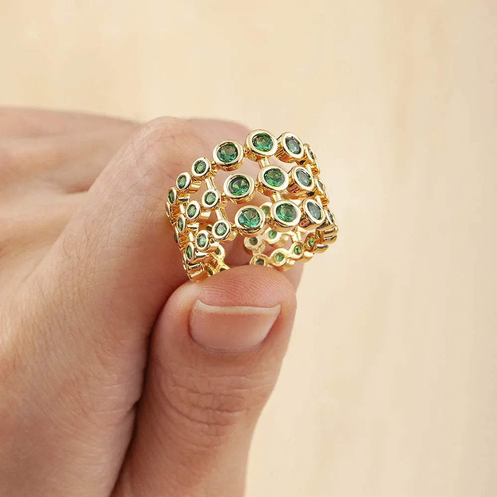 Gold-coloured exaggerated wide band ring with three-layer design and full green zircon stone setting.