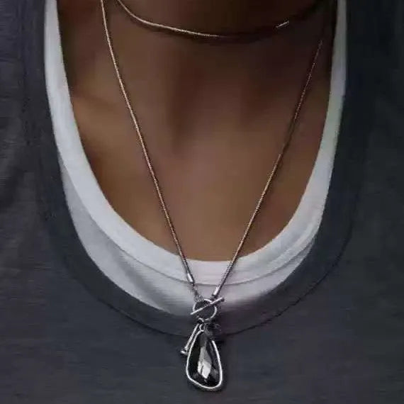 Long geometric alloy pendant necklace on a snake bones chain for sweaters.
