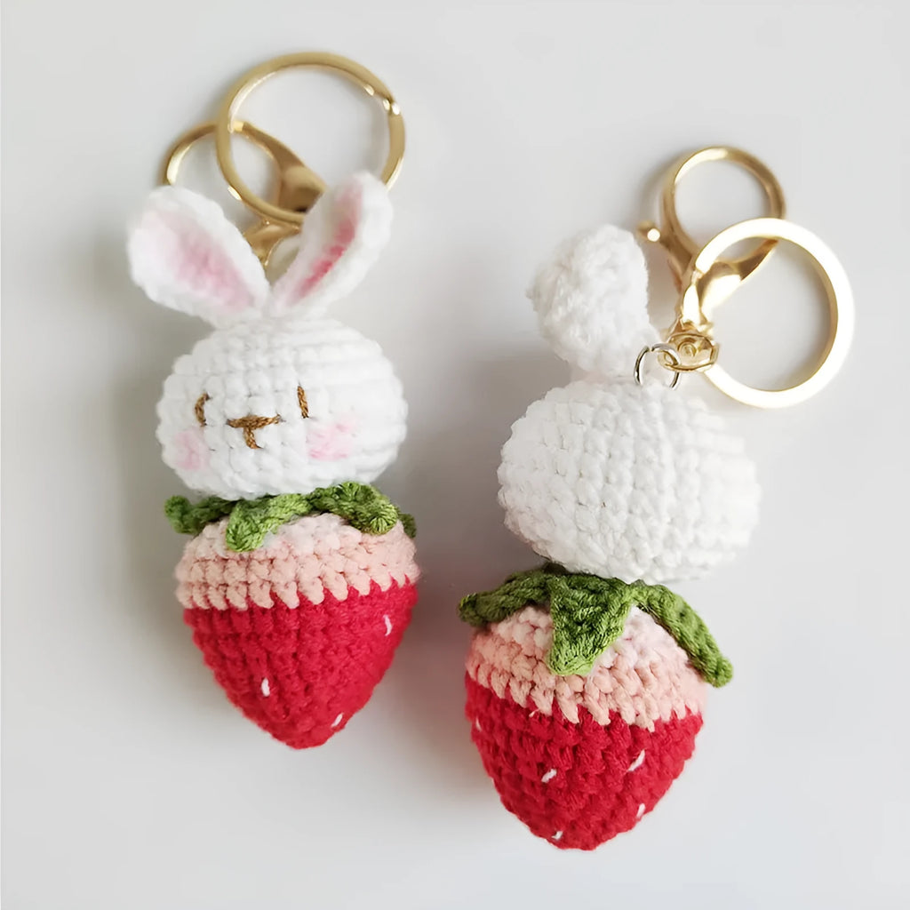 White hand-woven wire pendant with a cartoon rabbit strawberry design and an attached key.