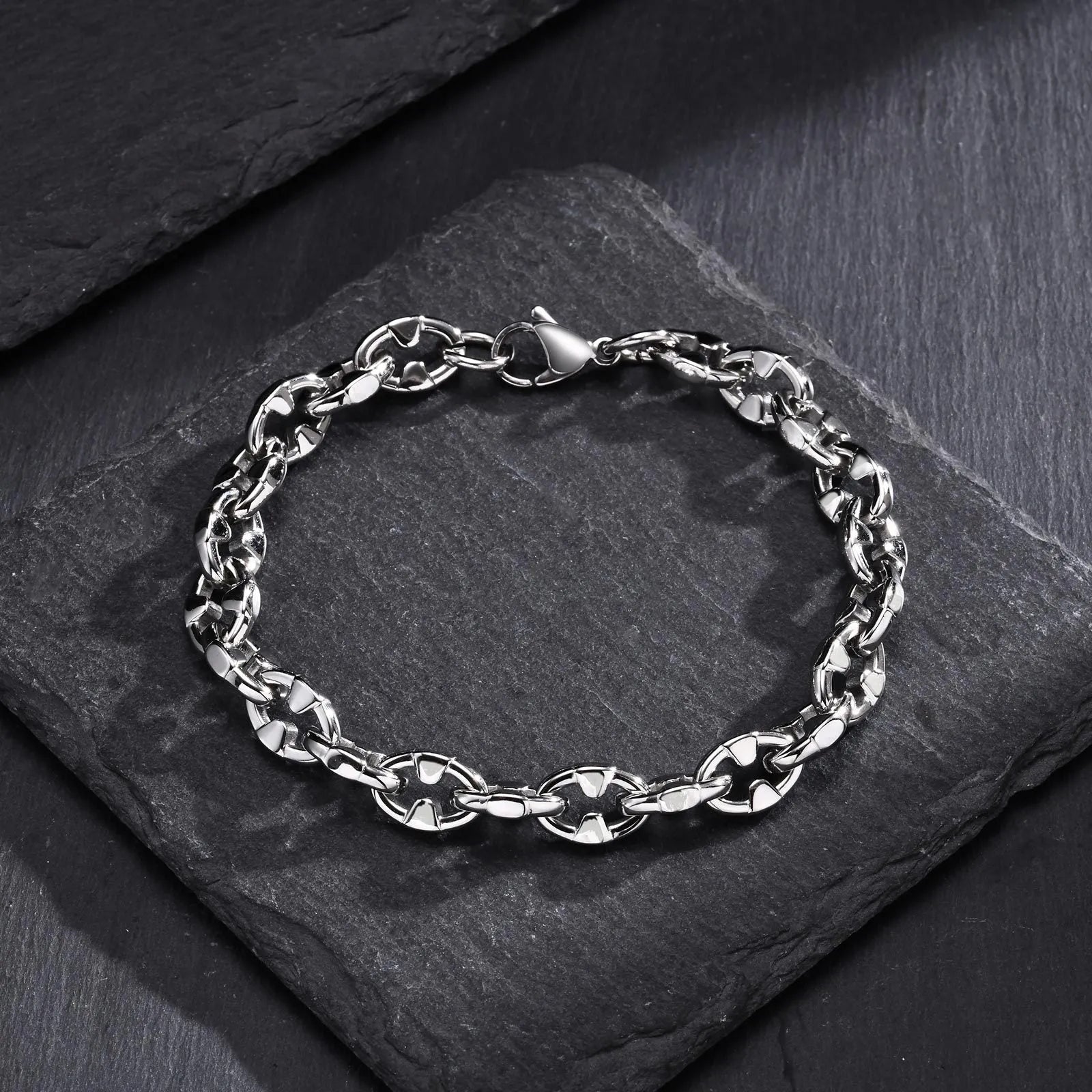 Handmade thick stainless steel geometric chain bracelet for men on a grey background.