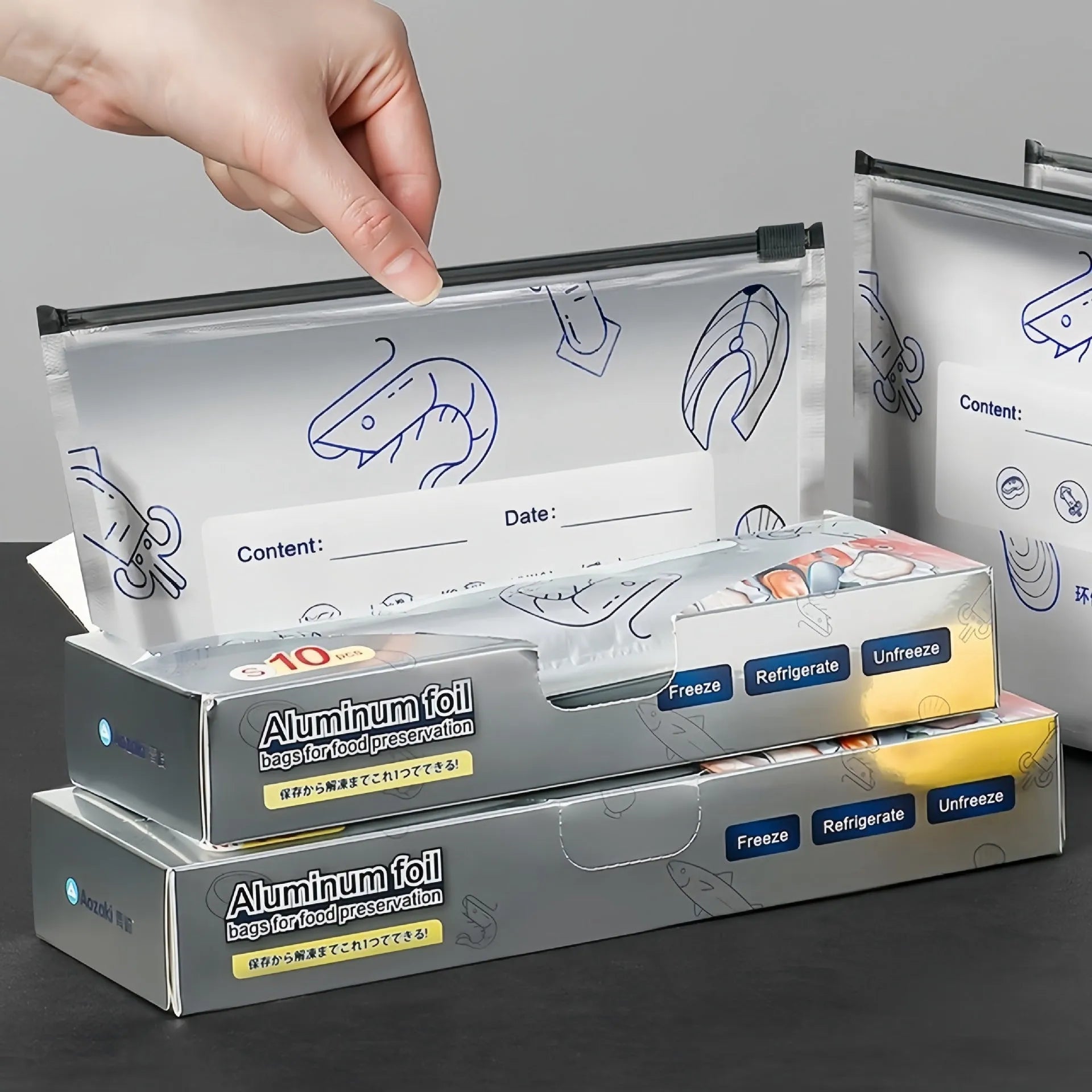 Set of aluminium foil sealed food storage bags and boxes in three different sizes on a kitchen counter.