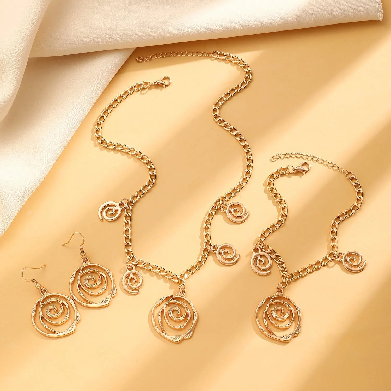 Spiral donut jewellery set with necklace, bracelet and ear hooks in gold or silver tone