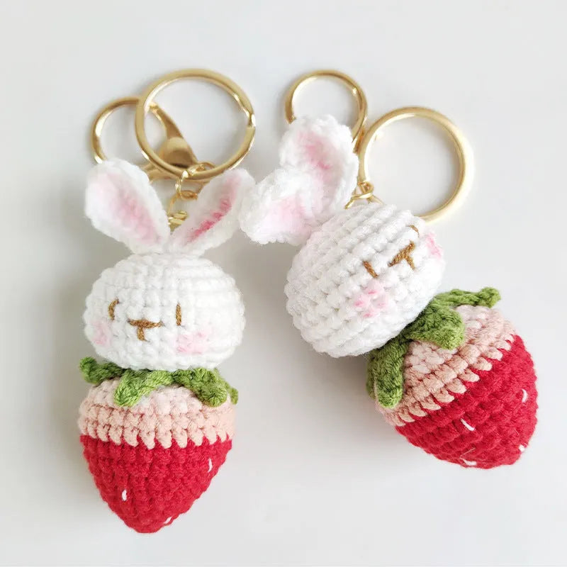 White hand-woven wire pendant with a cartoon rabbit strawberry design and an attached key.