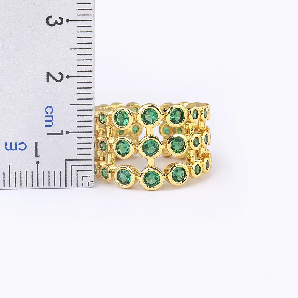 Gold-coloured exaggerated wide band ring with three-layer design and full green zircon stone setting.