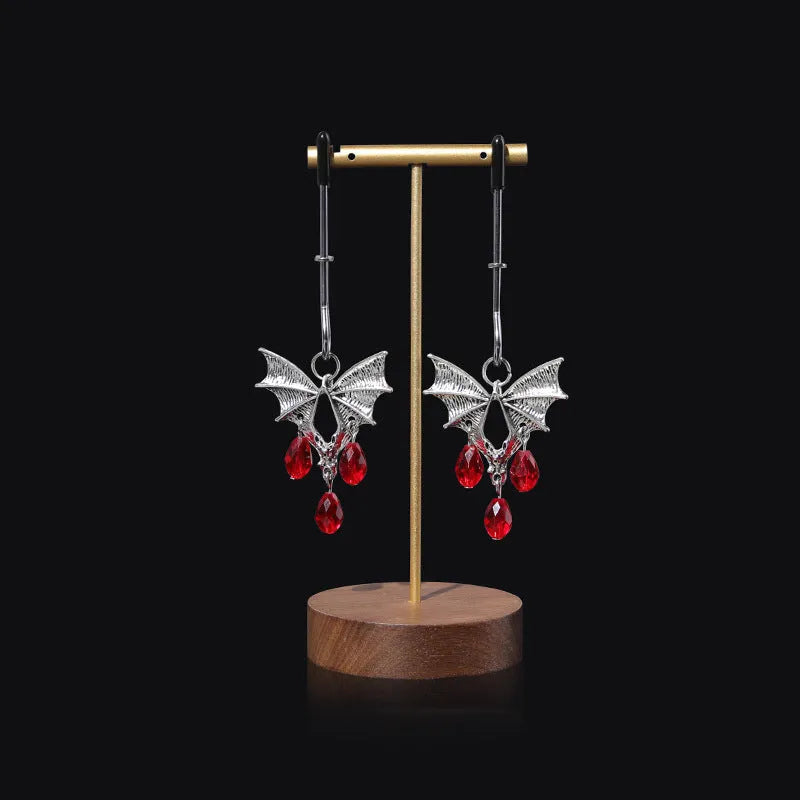 A pair of silver metal bat-shaped adjustable nipple clamps on a plain background.