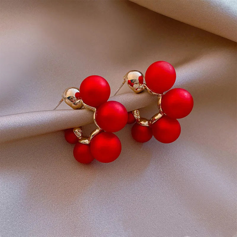 A pair of red bell-shaped alloy earrings for women on a white background.