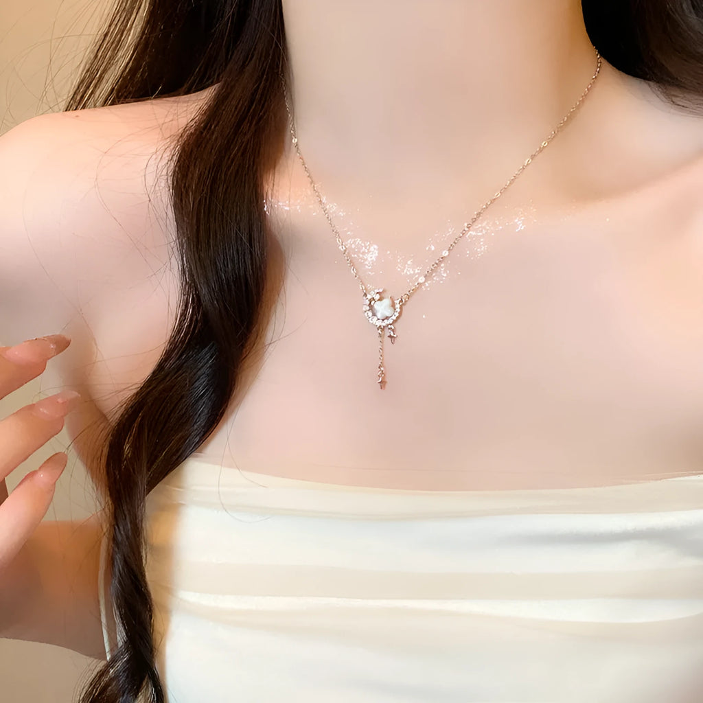 Gold star and moon pendant necklace on a model, showing adjustable clavicle chain.