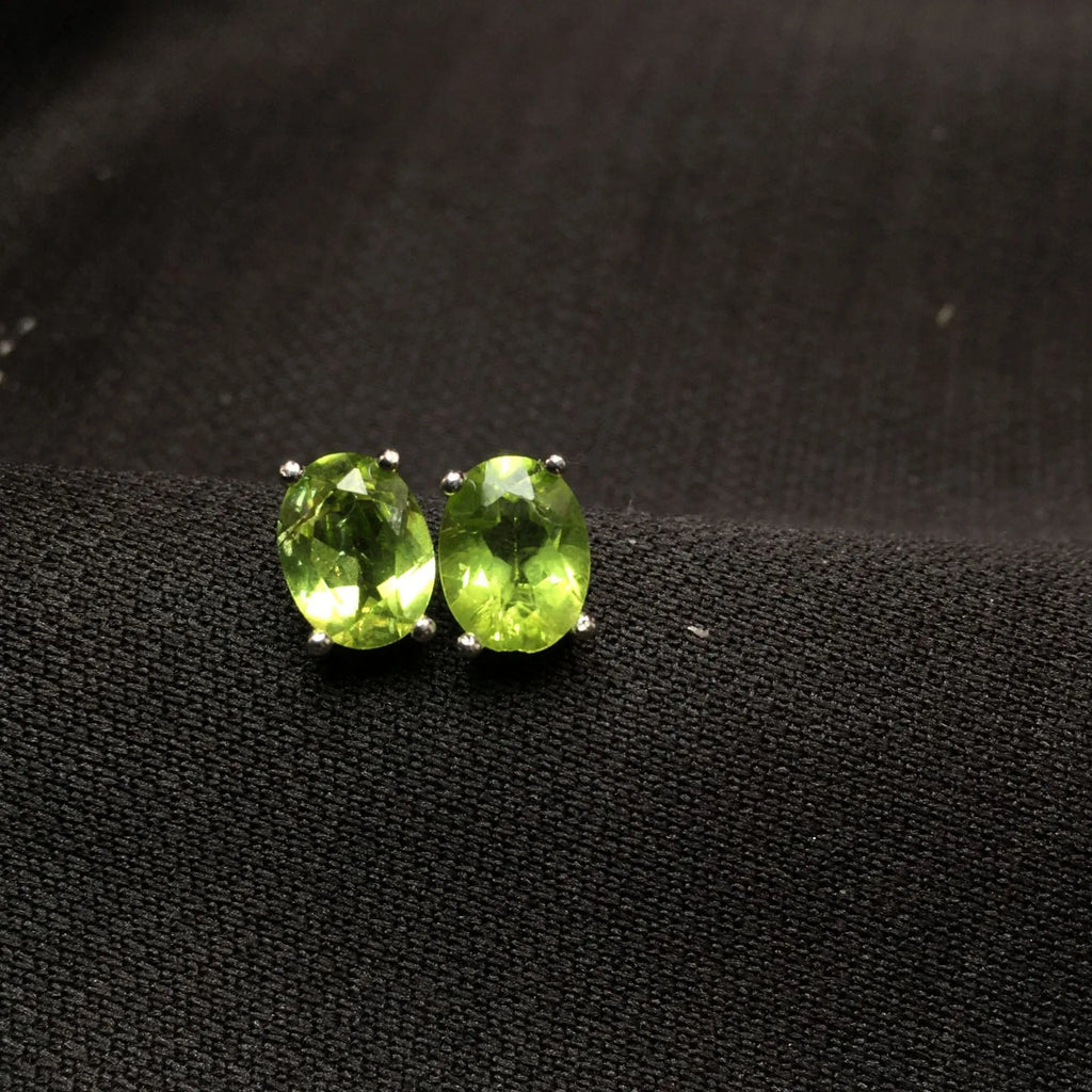 Close-up of natural grass green olivine stud earrings in S925 sterling silver settings.