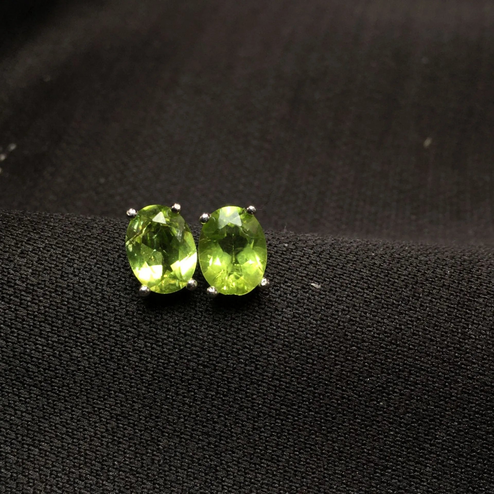 Close-up of natural grass green olivine stud earrings in S925 sterling silver settings.