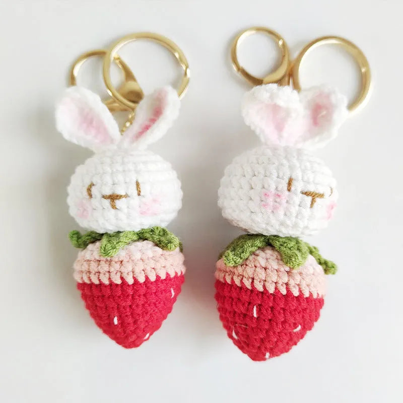 White hand-woven wire pendant with a cartoon rabbit strawberry design and an attached key.