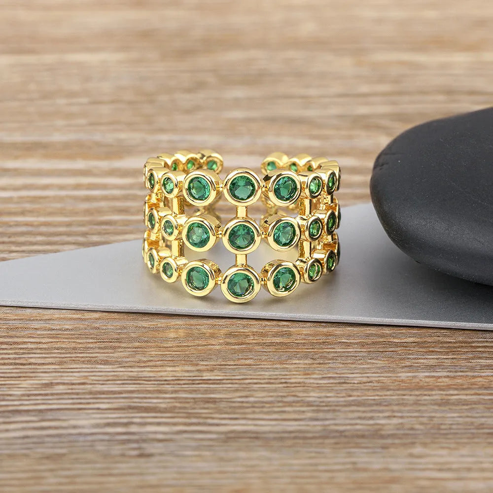Gold-coloured exaggerated wide band ring with three-layer design and full green zircon stone setting.
