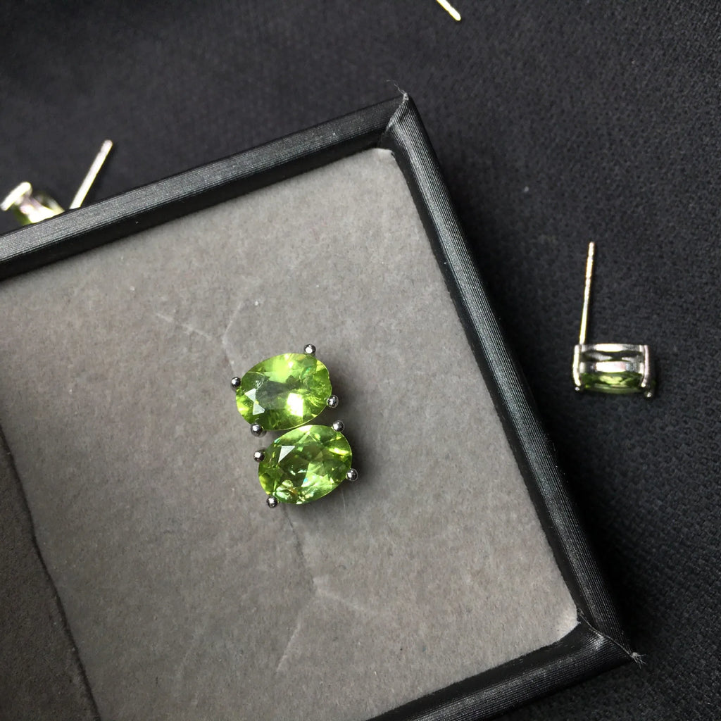 Close-up of natural grass green olivine stud earrings in S925 sterling silver settings.