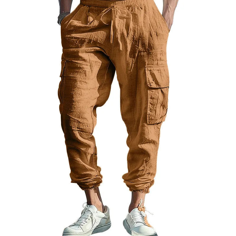Man wearing loose-fit linen trousers with ankle-tied cuffs and a multi-pocket tether detail.