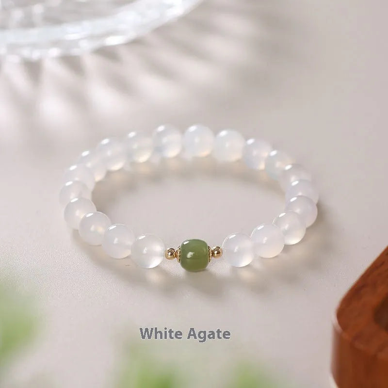 Handmade white agate bracelet with red cinnabar letter inlays on a wrist.