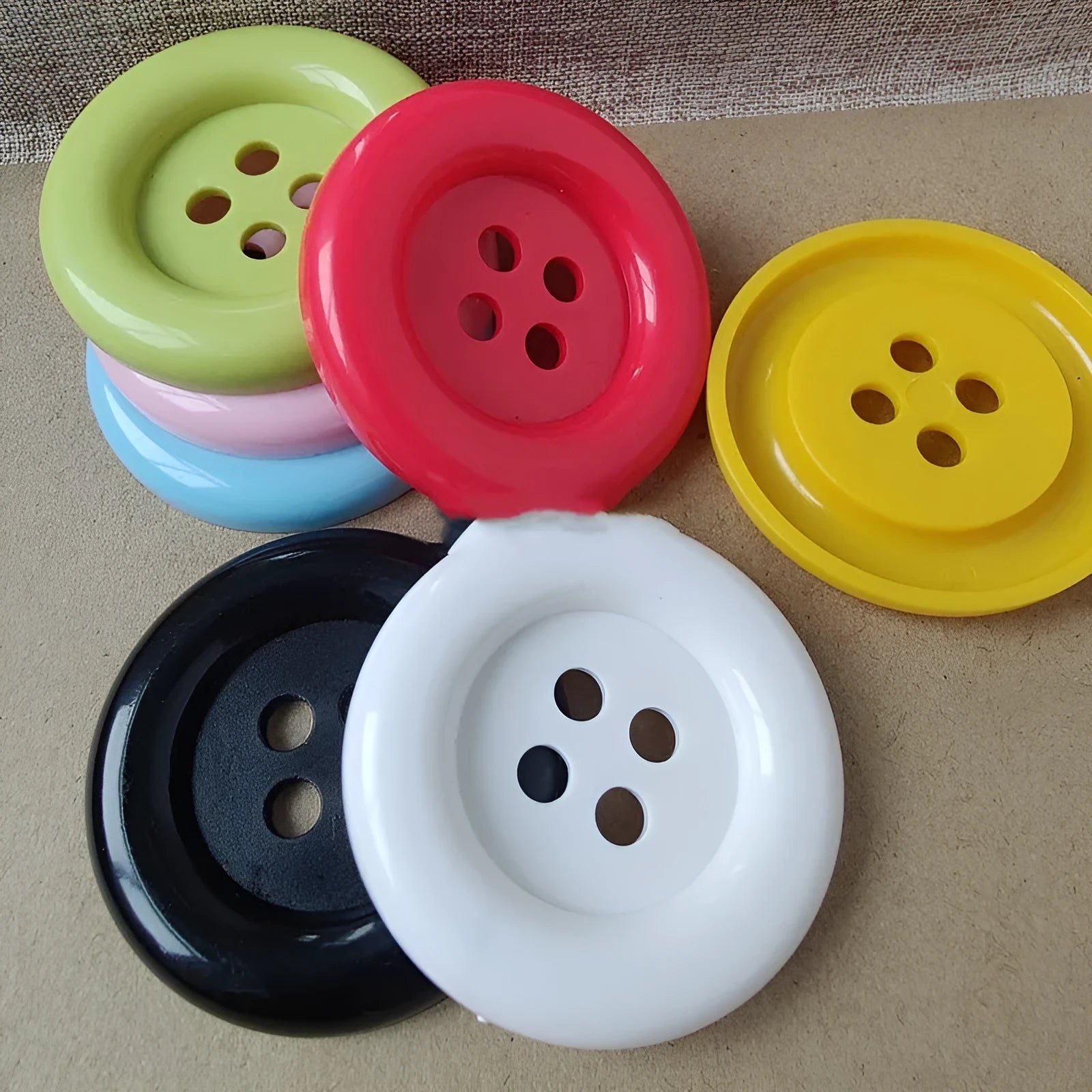Oversized round plastic nylon button with four holes in various colours and sizes
