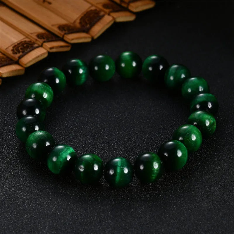 Green polished Tiger Eye stone bracelet with geometry beads on a wrist.