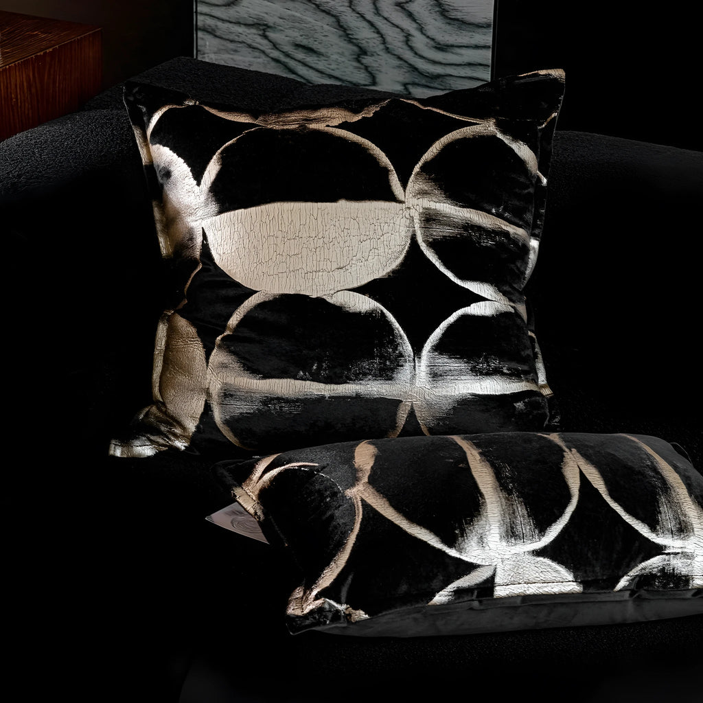 Black and gold abstract patterned square cushion on a grey sofa