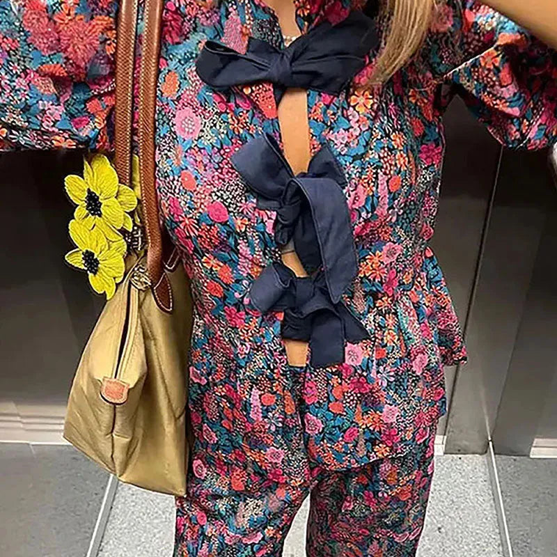 Women's floral print trousers suit with tie-neck blouse featuring puff sleeves and matching long trousers