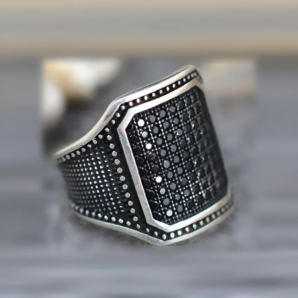 Black alloy ring with copper inlay surrounding a central zircon stone.