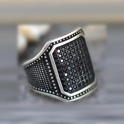 Black alloy ring with copper inlay surrounding a central zircon stone.