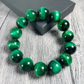 Green polished Tiger Eye stone bracelet with geometry beads on a wrist.