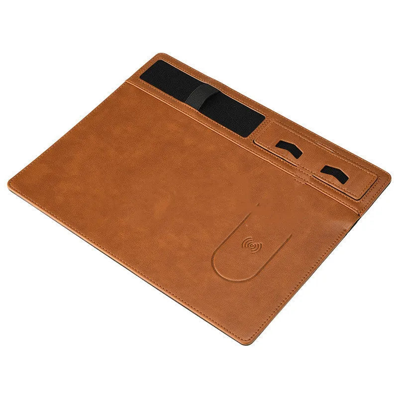 Pink wireless charging mouse pad with integrated phone holder on a wooden desk.