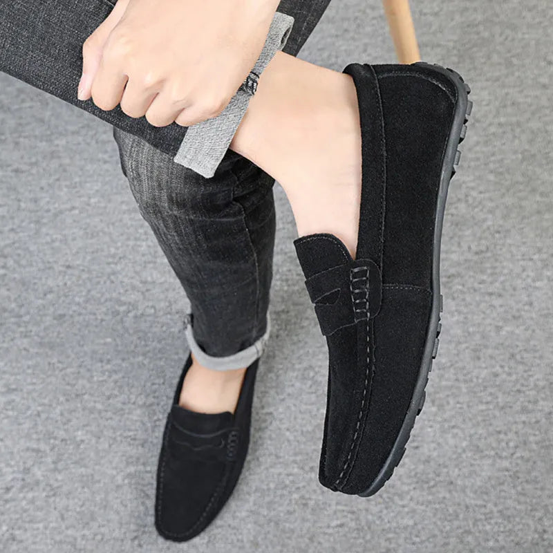 Men's solid colour suede loafers with a round toe and flat rubber sole on a neutral background.