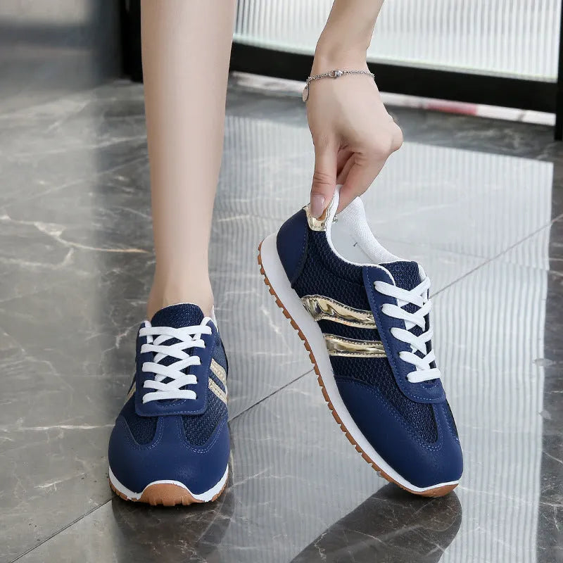 Blue women's casual tennis shoes with a cross shoulder strap and flat rubber sole on a white background.