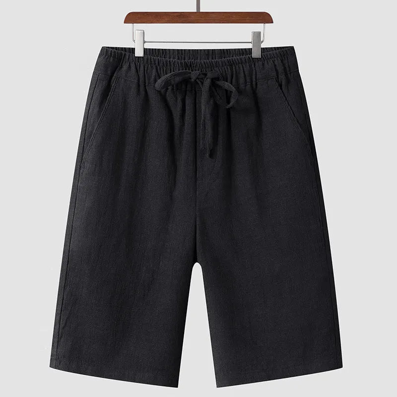 A pair of beige linen shorts for men with a loose, cropped fit and a mid-rise elasticated waistband.