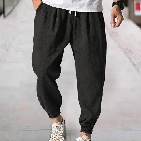 Men's loose-fitting cotton trousers with elasticated ankle bands in light green colour showing casual summer style