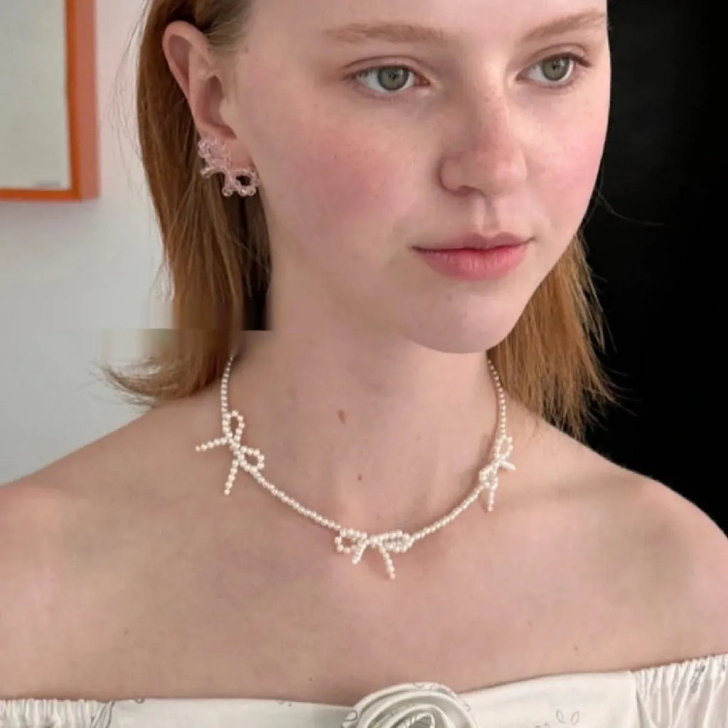 White imitation pearl necklace with a central bow pendant on a chain, adjustable from 31cm to 40cm.