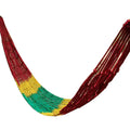 Green nylon rope mesh hammock hung between two trees showing its woven texture and length.