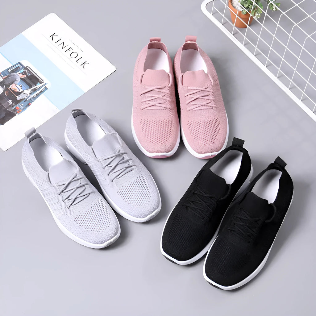 Women's grey lace-up sneakers with mesh upper and soft PVC sole on a light background.