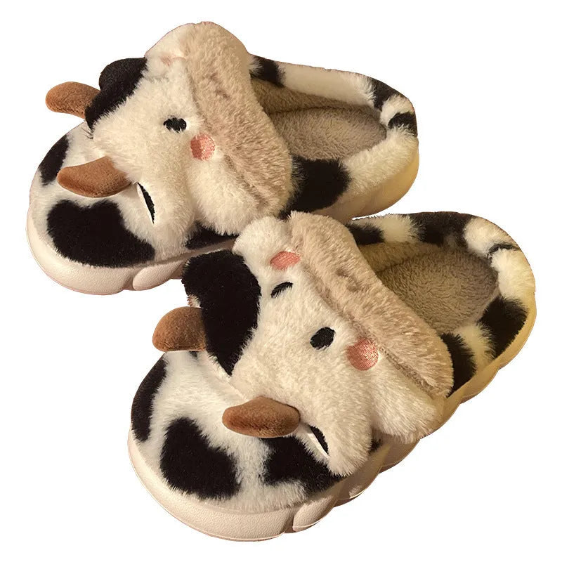 White cow-patterned plush slippers for women with a non-slip textured sole on a wooden floor