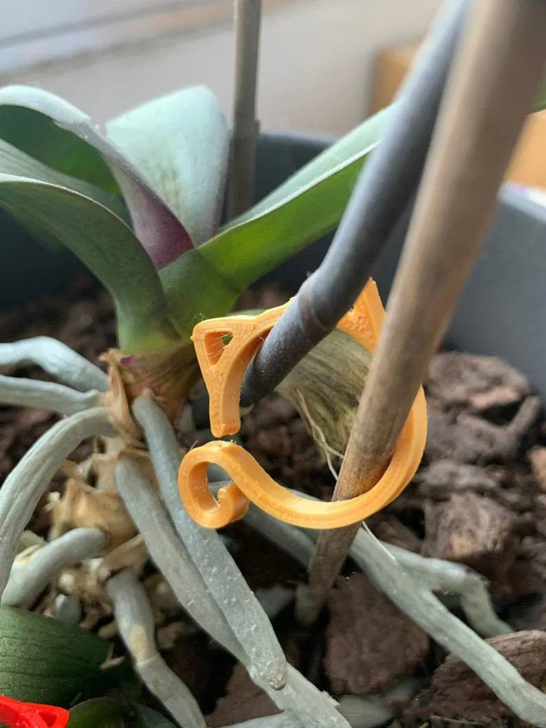 Red, yellow, green, and white cat-shaped plastic gardening clip for plant stems.