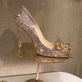 Women's gold pointed toe stiletto heels decorated with rhinestones and a bow