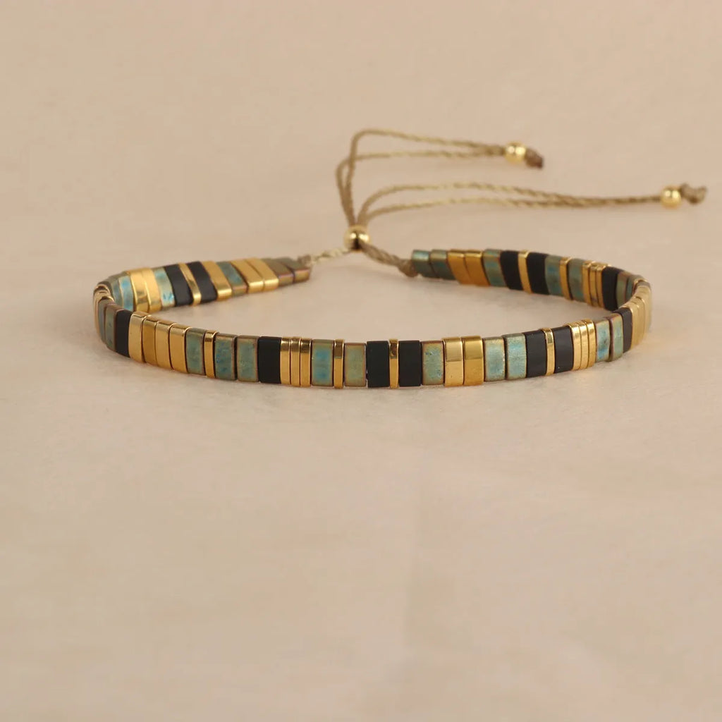 Geometric glass and coloured glaze beaded bracelet in milky white on a wrist.
