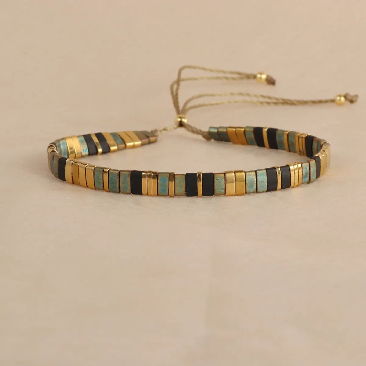 Geometric glass and coloured glaze beaded bracelet in milky white on a wrist.