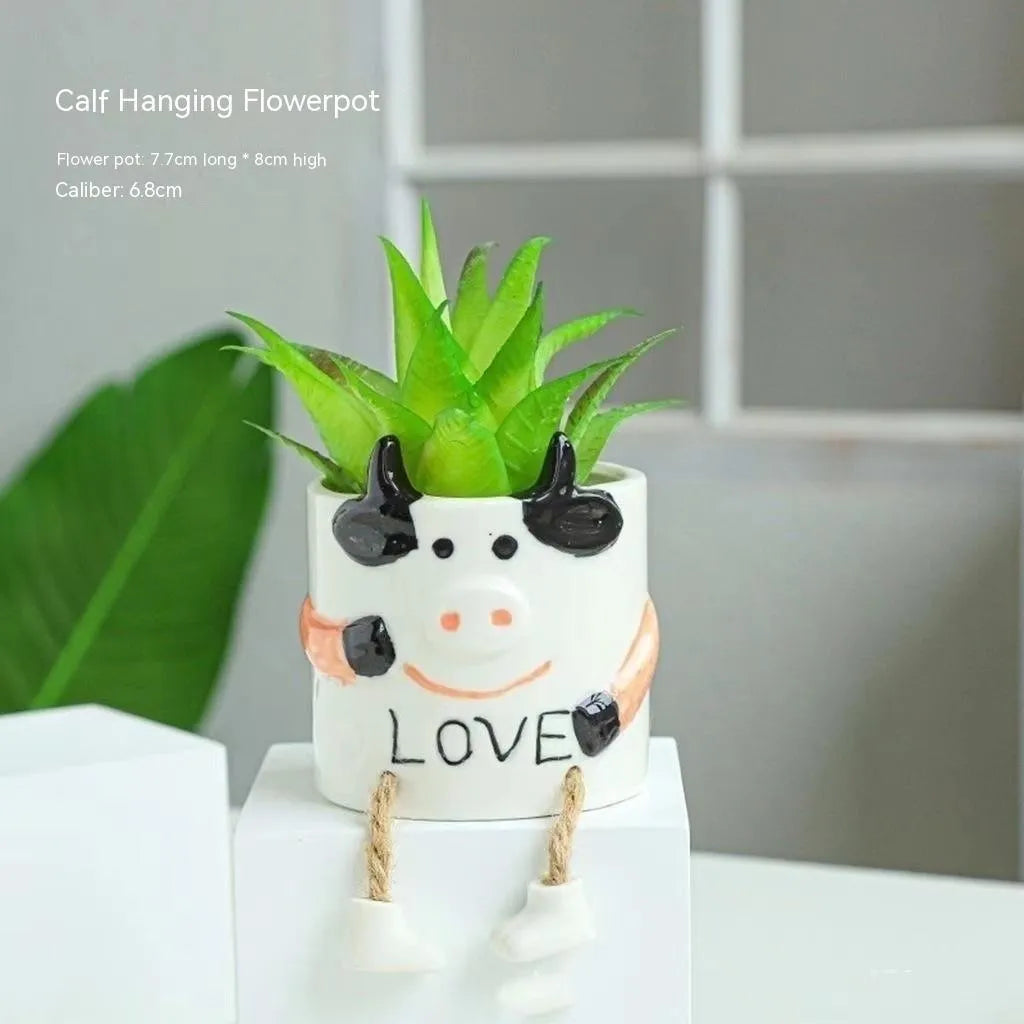 Ceramic cartoon-style hanging foot flowerpot for succulent plants on a desktop.