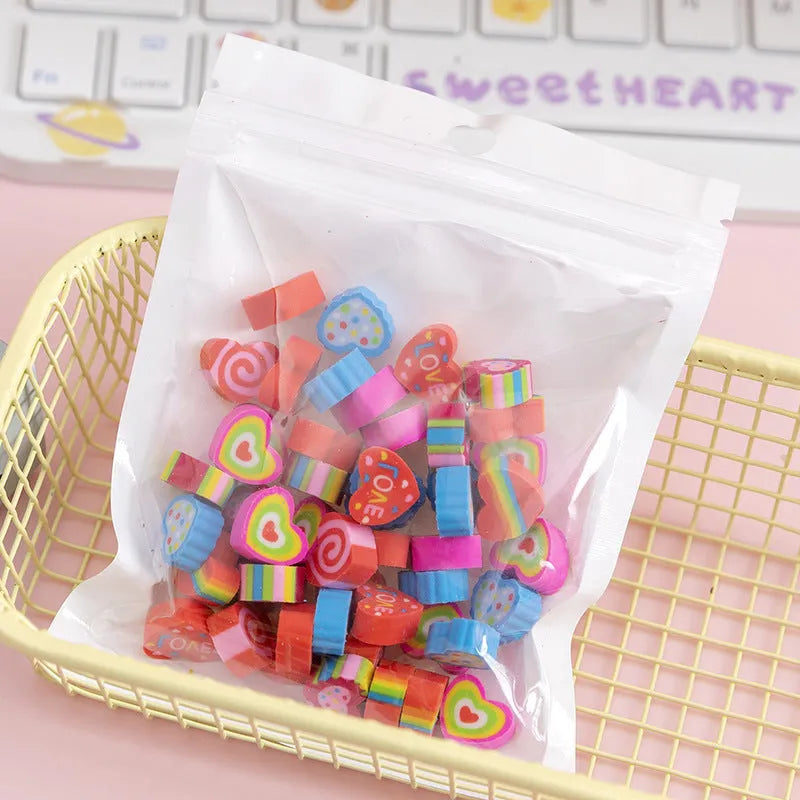Open pearlescent film bag showing 50 small colourful cartoon fruit-themed rubber erasers.
