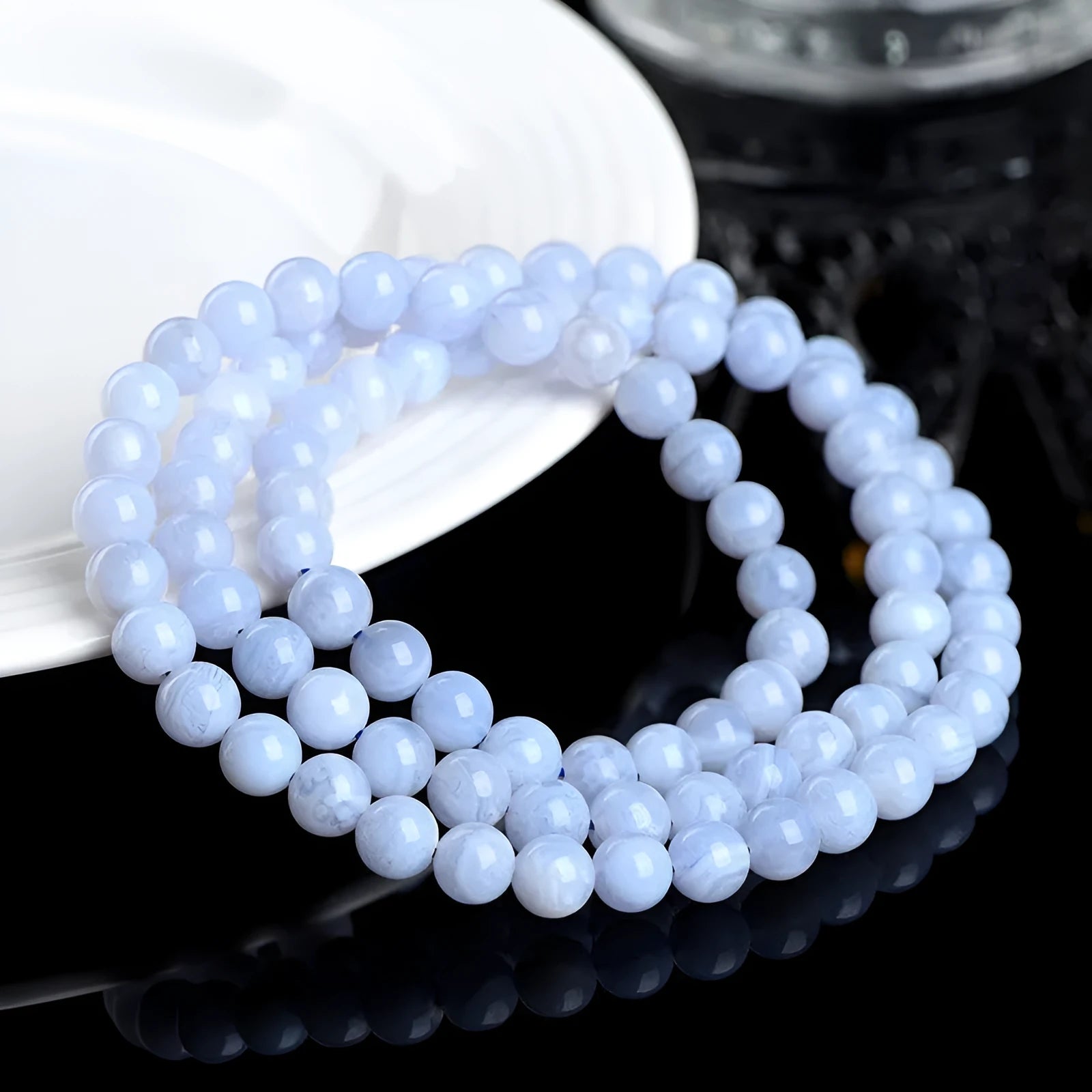 Close-up of a blue agate bracelet with multi-circle patterns, striped beads, and a Ruyi element on a neutral background.