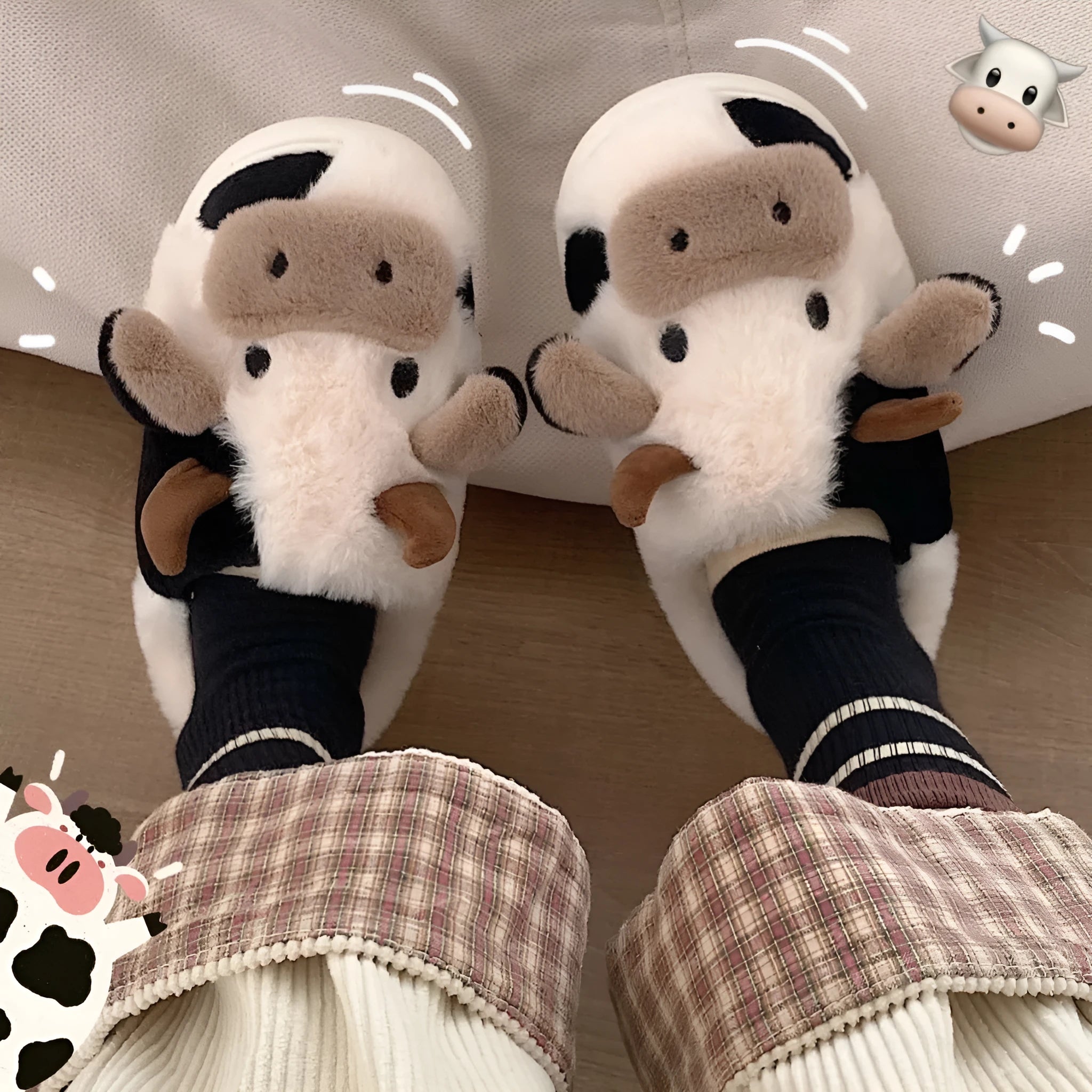 White cow-patterned plush slippers for women with a non-slip textured sole on a wooden floor