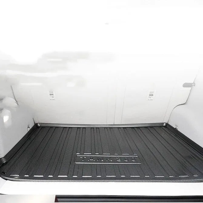 Black carbon fibre pattern TPE trunk pad installed in a car boot showing custom fit and textured surface
