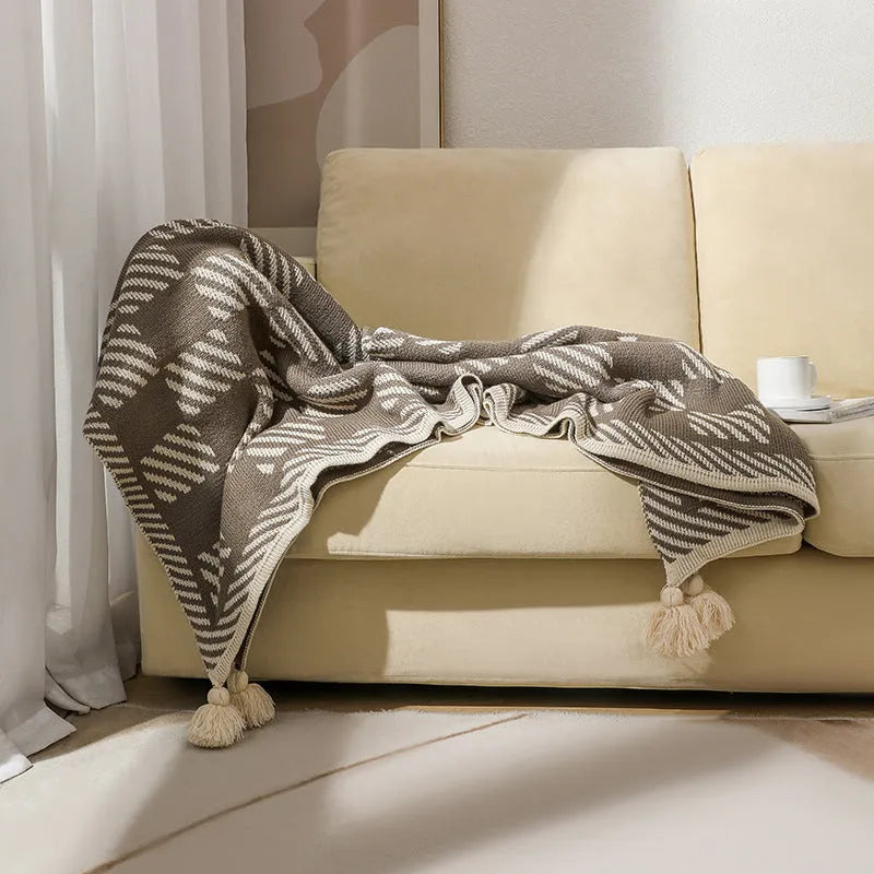 Bohemian style acrylic blanket with tassel fringe on a sofa, shown in a geometric print colour.