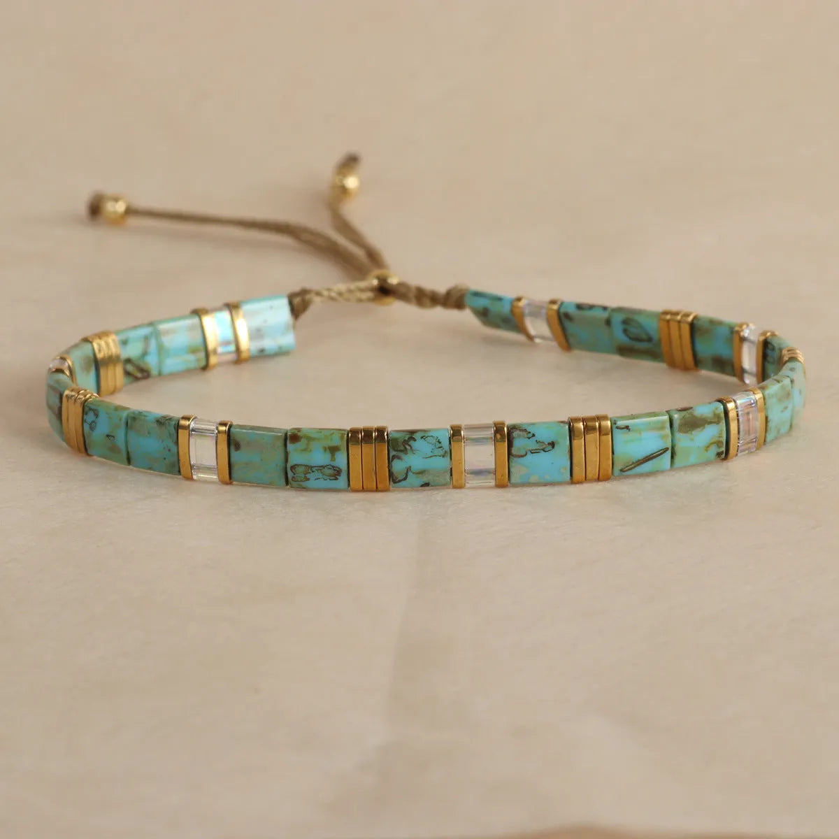 Geometric glass and coloured glaze beaded bracelet in milky white on a wrist.