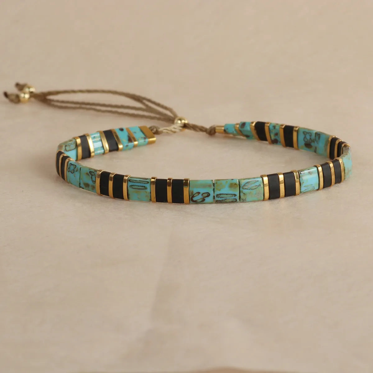 Geometric glass and coloured glaze beaded bracelet in milky white on a wrist.