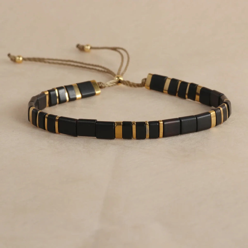 Geometric glass and coloured glaze beaded bracelet in milky white on a wrist.