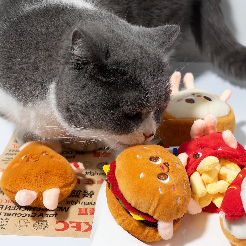 Set of four soft fabric cat chew toys shaped like a hamburger, chicken leg, fries, and hot dog on a plain background.