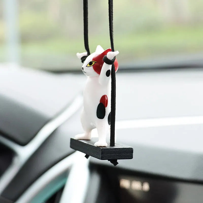 Cartoon-style resin cat pendant on a rope hanger for car interior decoration.
